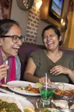 Three people laugh while enjoying a meal together.